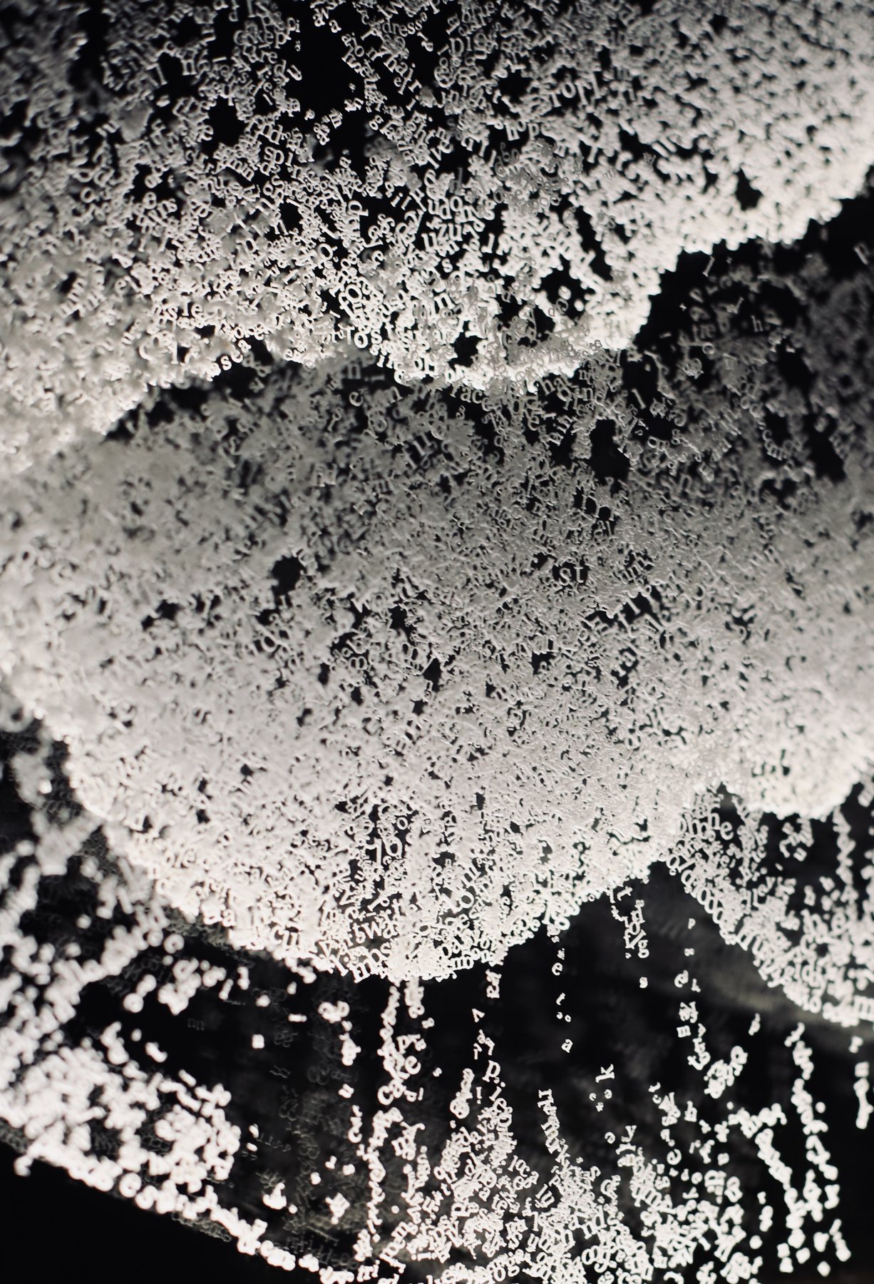 Close-up of overlapping letters forming dense wave-like textures.
