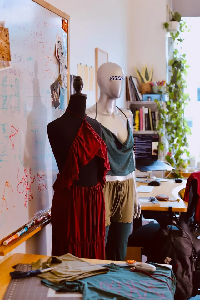 Garments on mannequins beside a studio desk