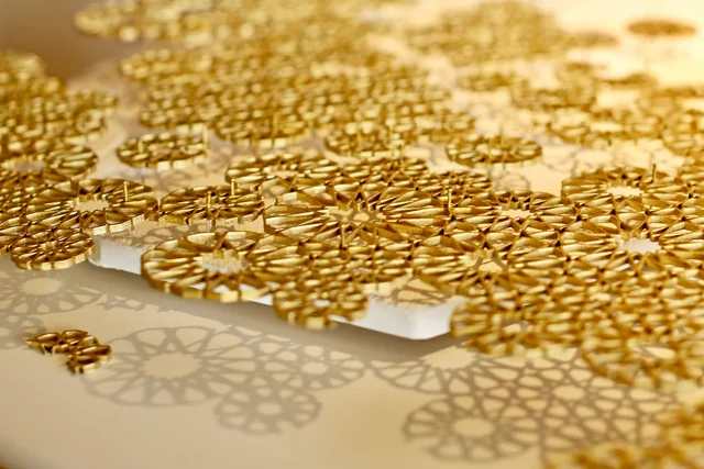 Close-up of gold rosette forms casting patterned shadows on a pale surface