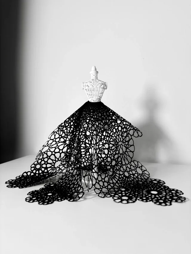 Front view of a miniature dress form wearing a black rosette-patterned skirt