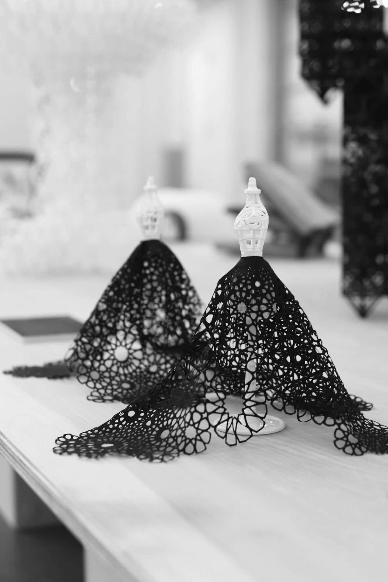 Two black cutwork textile sculptures displayed on miniature dress forms at Polymaths