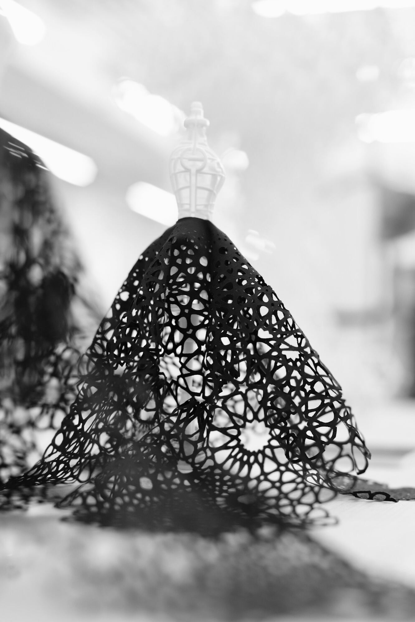 Backlit detail of a black cutwork textile sculpture at Polymaths